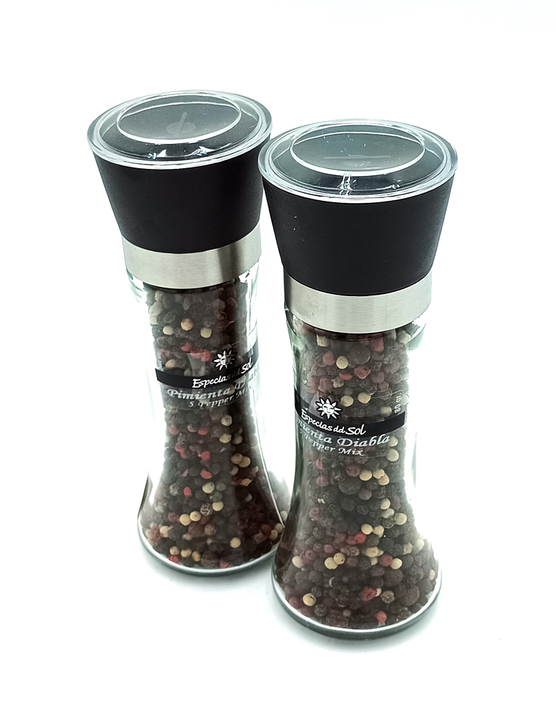 1776794963776 - El Gourmext de Casa Chino Two clear glass pepper grinders with black tops and metal bands, filled with mixed peppercorns on a white background, front view.
