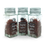 Three glass spice jars with metal lids, filled with saffron threads and labeled Azafrán Saffron (net wt. 5 g each).