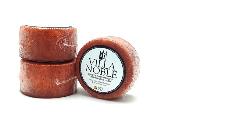 Three red cheese wheels, two stacked with a third leaning, labeled Villa Noble on a white background.