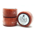 Three red goat cheese wheels stacked, one showing a Villa Noble label.