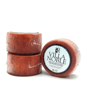 Three red goat cheese wheels stacked, one showing a Villa Noble label.
