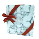 Marble-pattern blue gift box with a red ribbon tied in a bow and ‘BOLCI CHOCOLATE’ logo on the front (308g).] ,