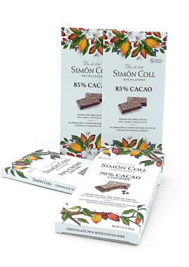 Simon Coll chocolate bars with 85% cacao on white wrappers, decorated with a colorful fruit and leaf border; three bars arranged (one upright, two flat).