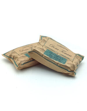 Two wrapped tins (tuna) in brown paper with turquoise labels, one resting on top of the other; label reads 'Ventresca de atún en aceite de oliva' from Conservas Dona Tomasa