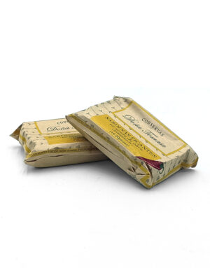 Two beige, vintage-style wrapped cans (likely sardines) resting on a white surface.