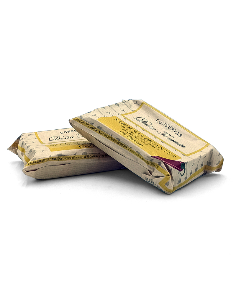 1777484625264 - El Gourmext de Casa Chino Two wrapped cans of sardines in beige parchment-style packaging, stacked on a white background.