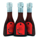 Three bottles of smoked paprika sauce with red labels and blue-tinted caps, arranged in a row on a white background, brand Chinata.