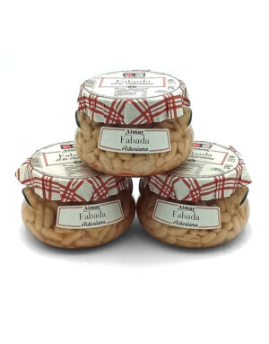 Three glass jars of Aimar Fabada Asturiana beans stacked in a pyramid on a white background with red plaid lids and labels.
