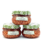 Three glass jars labeled Garbanzos con bacalao with green checkered lids on a white background.