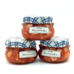 Three glass Marmitako jars with blue plaid lids stacked against a white background, displaying the product.