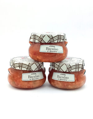 Three glass jars of Bacalao cod in tomato sauce with plaid metal lids, arranged in a pyramid on a white background.