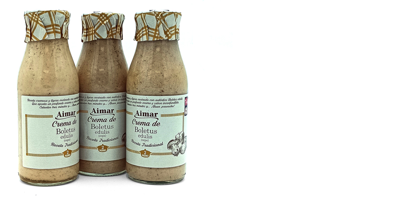 Three bottles of Aimar Crema de Boletus edulis cream on a white background, with patterned foil tops tied around the caps.