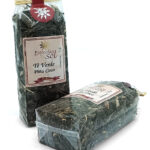 1776794963571 - El Gourmext de Casa Chino Two packaged tea bags of Especias del Sol Te Verde Piña Coco, green tea with pineapple coconut scent, in clear plastic wrapping on a white background (front and side views).