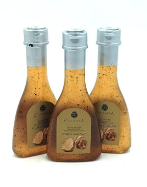Three glass bottles of truffle balsamic sauce with light brown liquid and specks, labeled Trufa Blanca by Chinata, arranged in a row against a white background.