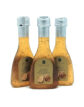 Three glass bottles of truffle white balsamic vinegar with beige labels on a white background.