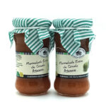 1778794818258 - El Gourmext de Casa Chino Two jars of artisanal plum jam with green-and-white striped cloth lids and beige labels.