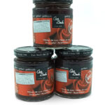 Three Can Bech rose-petal jam jars stacked—two on the bottom and one on top, with dark glass and red labels.
