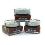 Three square glass jars of brown nail polish with gray patterned caps, branded 'zalama' on the front, arranged in a stack on a white background.