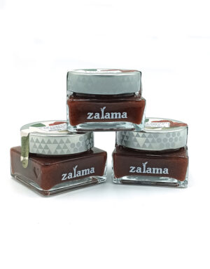 1778794818683 - El Gourmext de Casa Chino Three square glass jars of brown nail polish with gray patterned caps, branded 'zalama' on the front, arranged in a stack on a white background.