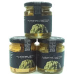 1778794819231 - El Gourmext de Casa Chino Three glass jars of artichokes confit in extra virgin olive oil on a white background, labels visible on each jar.