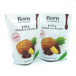 1778794820593 - El Gourmext de Casa Chino Two white standing pouches labeled Born Piña chocolate-covered dried pineapple treats, shown with pineapple and chocolate pieces on the front.