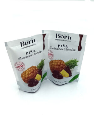 1778794820620 - El Gourmext de Casa Chino Two white bags of Born Piña Bañada en Chocolate dried pineapple treats, featuring pineapple and chocolate images on the front.