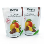 1778794820736 - El Gourmext de Casa Chino Two white pouches of Born Mango Bañado en Chocolate, mango and chocolate pieces illustrated, packaging showing 'Fruta Deshidratada' and green label highlights.