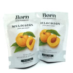 Two white stand-up pouches of Born dried peaches (Melocotón) with peach illustration and green leaves on the front, text in Spanish.